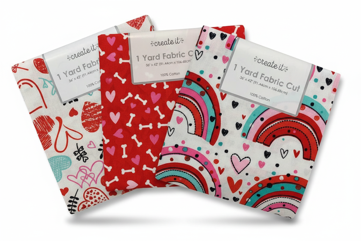 Three Create It Valentine quilting cotton 1 yard fabric cuts fanned out on a white background: scribble hearts print, red bones print, and rainbow hearts print