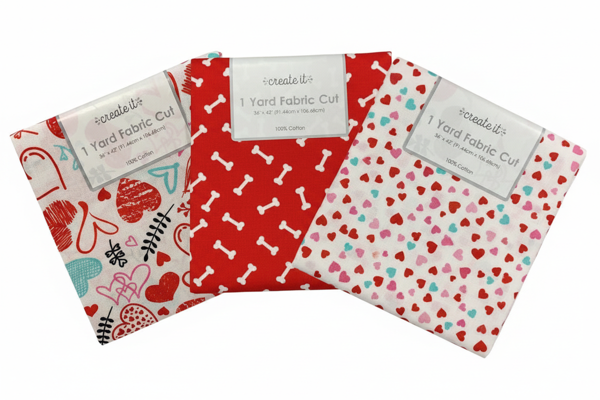 Three Create It Valentine quilting cotton 1 yard fabric cuts fanned out on a white background: scribble hearts print, red dog bones print, and small hearts print